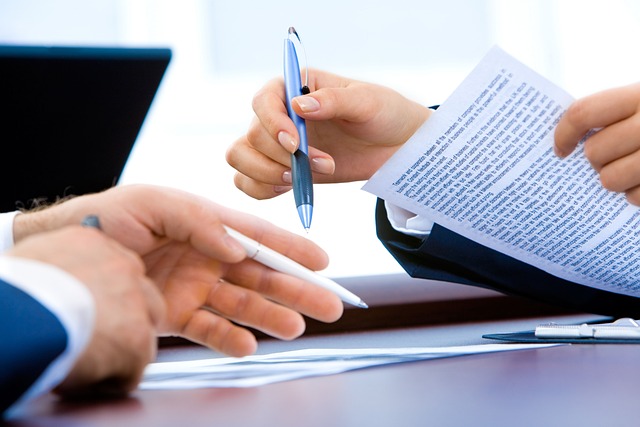 Laptop on a desk with documents and handwriting notes