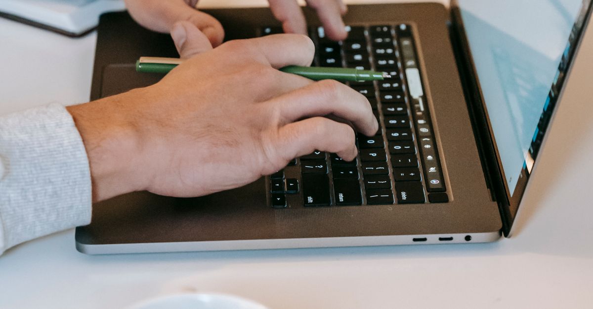 Person working on a laptop at a cafe with a coffee cup